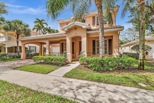 mediterranean / spanish home featuring a tiled roof, a porch, and stucco siding