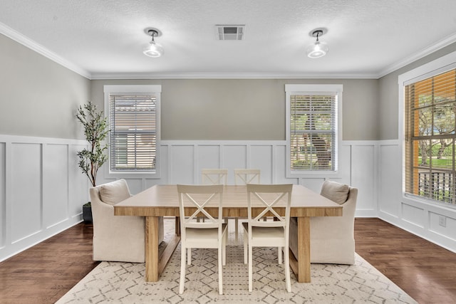 dining room with ornamental molding, visible vents, a textured ceiling, and wood finished floors