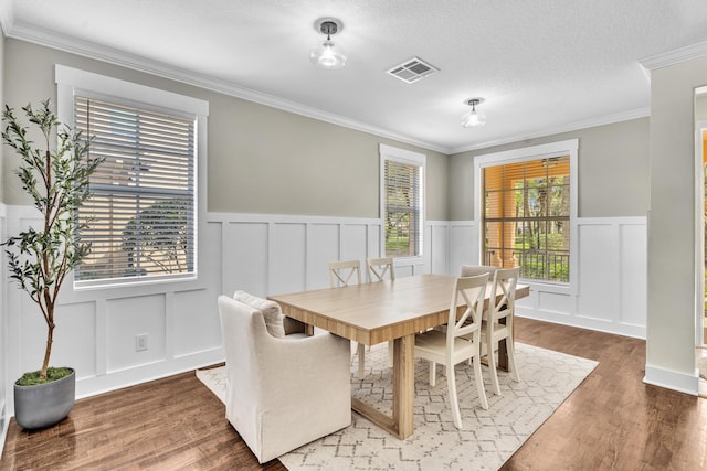 dining space featuring visible vents, a decorative wall, and wood finished floors