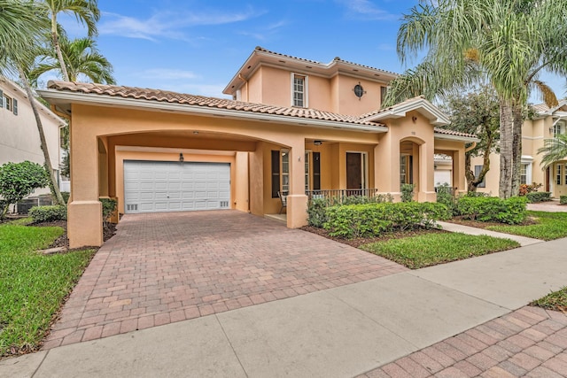 mediterranean / spanish-style house featuring a garage, decorative driveway, a tiled roof, and stucco siding