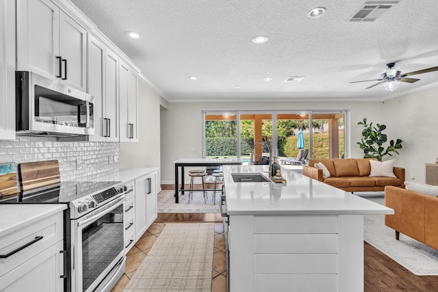 kitchen featuring crown molding, light countertops, visible vents, decorative backsplash, and appliances with stainless steel finishes