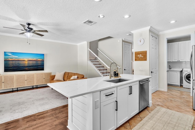 kitchen with a center island with sink, visible vents, open floor plan, a sink, and stainless steel dishwasher