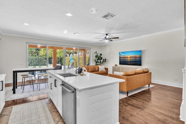 kitchen with stainless steel dishwasher, ornamental molding, light countertops, and a sink