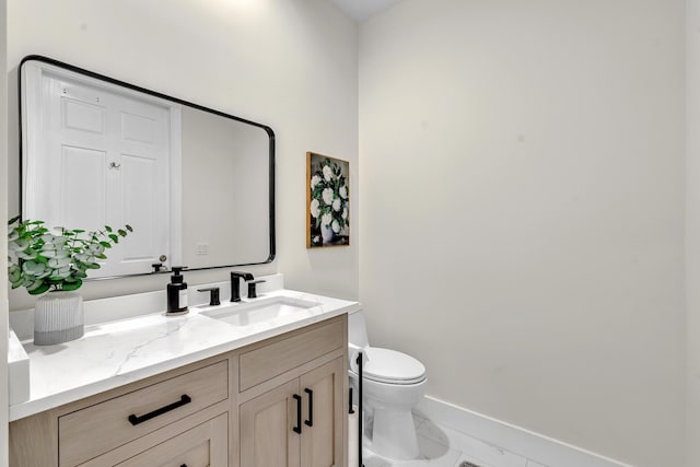 bathroom featuring marble finish floor, baseboards, vanity, and toilet