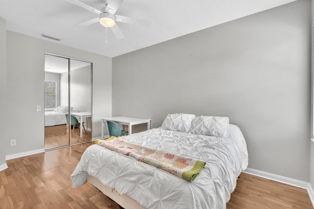 bedroom with baseboards, a closet, visible vents, and wood finished floors