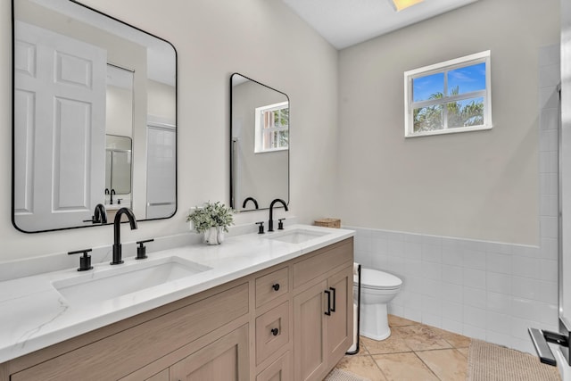 bathroom with a stall shower, a sink, toilet, and double vanity