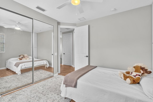 bedroom with baseboards, wood finished floors, visible vents, and a ceiling fan