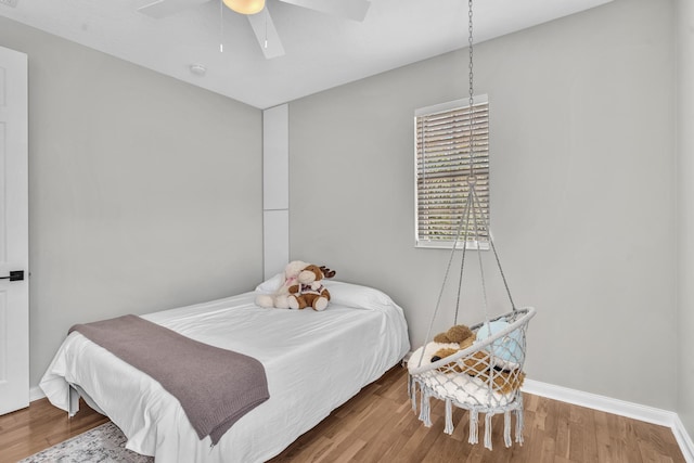 bedroom with a ceiling fan, baseboards, and wood finished floors