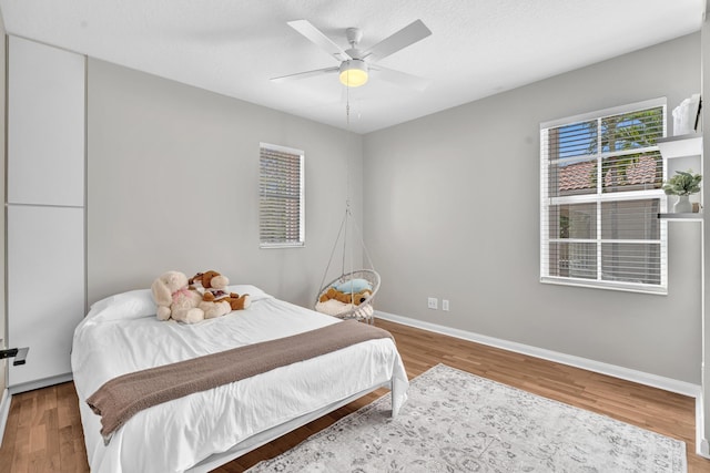 bedroom featuring a textured ceiling, wood finished floors, a ceiling fan, and baseboards