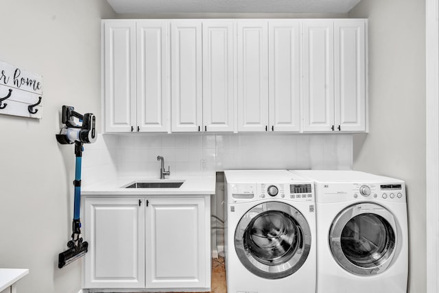 washroom with cabinet space, a sink, and washing machine and clothes dryer