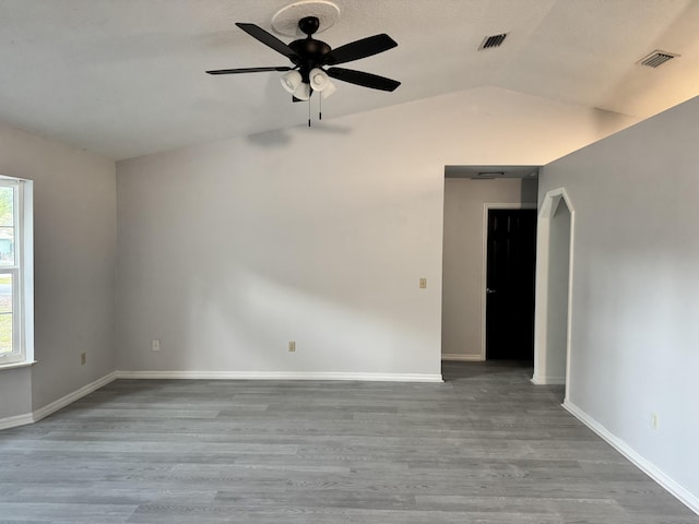 unfurnished room with visible vents, wood finished floors, ceiling fan, and vaulted ceiling
