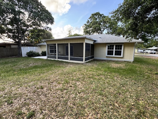 back of property with a sunroom, a lawn, and fence