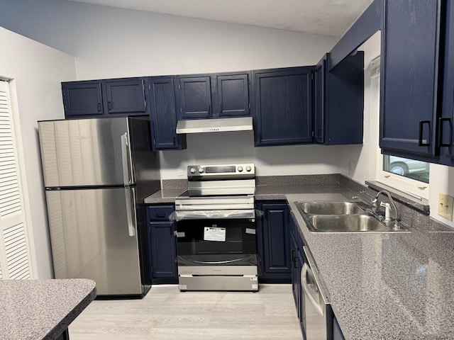 kitchen featuring blue cabinetry, appliances with stainless steel finishes, vaulted ceiling, a sink, and light wood-type flooring