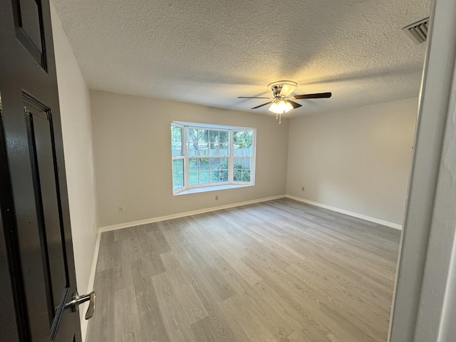 unfurnished bedroom featuring a textured ceiling, wood finished floors, visible vents, and baseboards