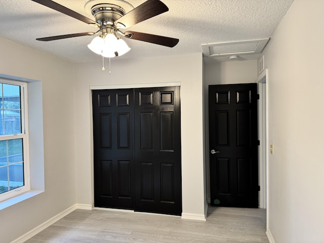 foyer with a textured ceiling, ceiling fan, light wood-style flooring, and baseboards