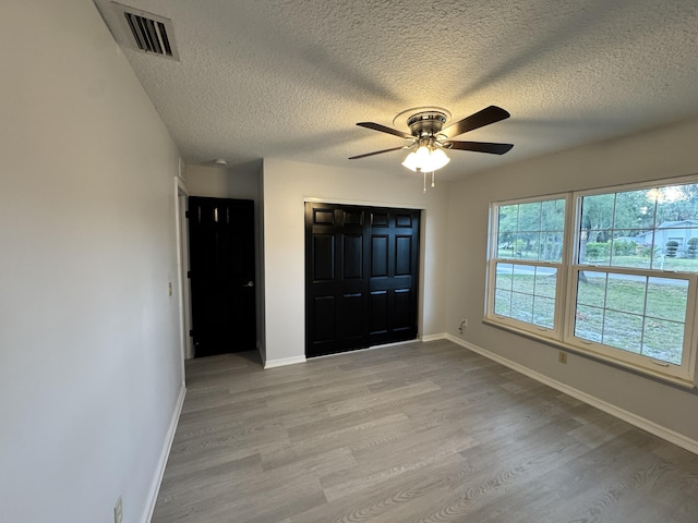 foyer featuring a textured ceiling, light wood-style floors, ceiling fan, visible vents, and baseboards