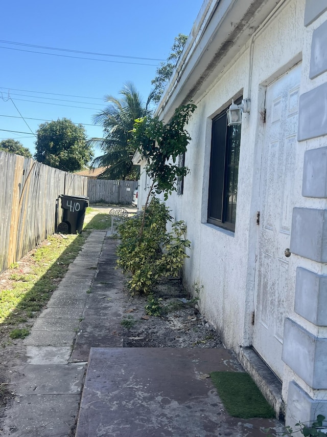 view of side of home featuring fence and stucco siding