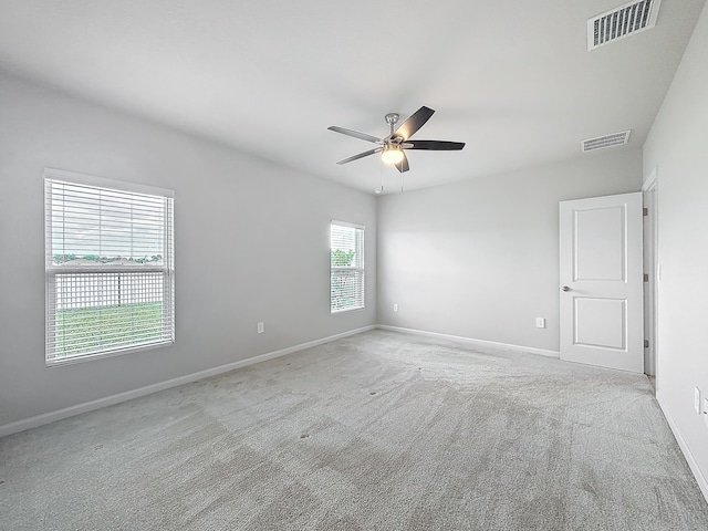 unfurnished room with light colored carpet, visible vents, ceiling fan, and baseboards