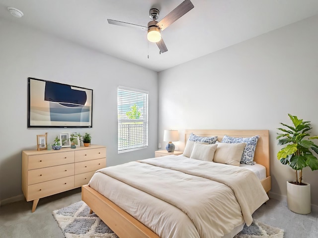 bedroom featuring light carpet, a ceiling fan, and baseboards