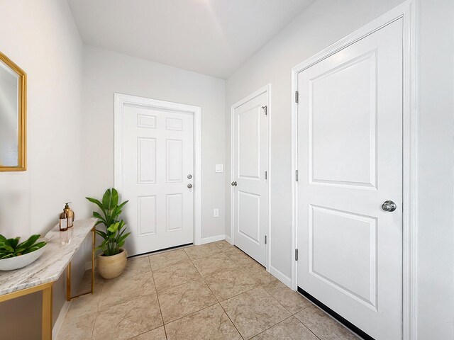 doorway to outside featuring light tile patterned floors and baseboards