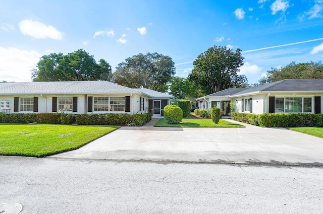 ranch-style home featuring brick siding, concrete driveway, and a front yard