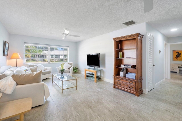 living room featuring baseboards, a textured ceiling, visible vents, and a ceiling fan