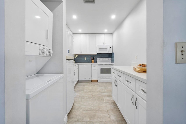 kitchen with stacked washer and dryer, white appliances, light countertops, and white cabinets