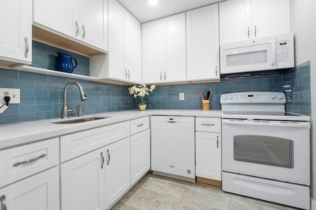 kitchen featuring white appliances, white cabinets, and a sink