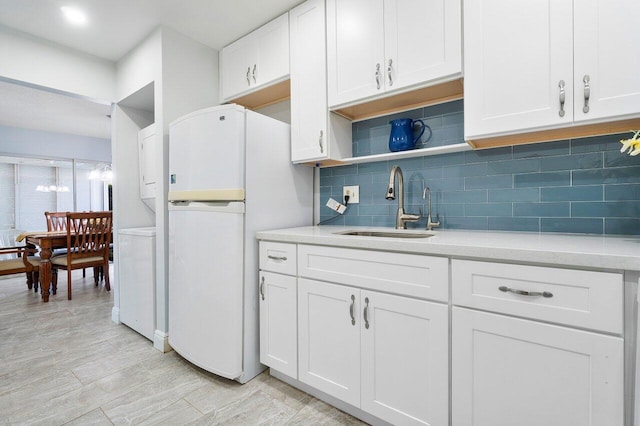 kitchen with a sink, white cabinets, light countertops, freestanding refrigerator, and open shelves