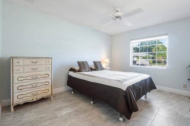 bedroom featuring a ceiling fan, baseboards, and a textured ceiling