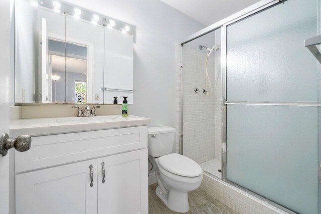 bathroom with a stall shower, vanity, and toilet