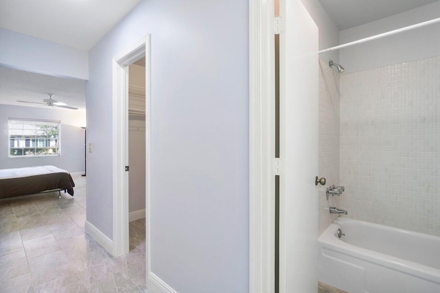 ensuite bathroom featuring tub / shower combination, connected bathroom, ceiling fan, tile patterned flooring, and baseboards