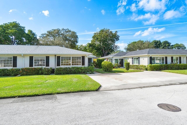 single story home featuring brick siding, driveway, and a front lawn