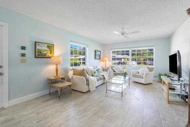 living room with a textured ceiling, baseboards, a ceiling fan, and a healthy amount of sunlight