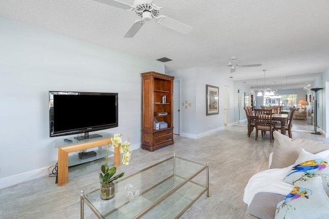 living room featuring a ceiling fan, visible vents, baseboards, and a textured ceiling