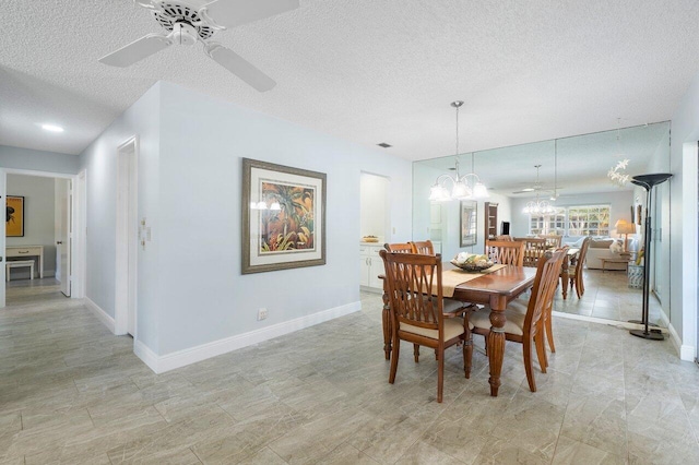 dining space with a textured ceiling, ceiling fan with notable chandelier, and baseboards