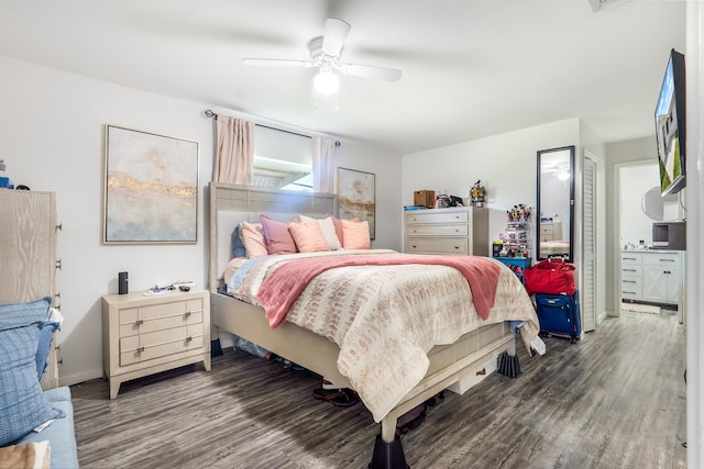 bedroom featuring ensuite bathroom, dark wood-style flooring, a ceiling fan, and baseboards