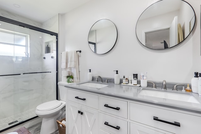 full bath featuring a sink, a shower stall, toilet, and double vanity