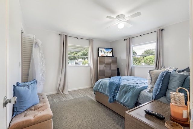 bedroom with light wood-style floors, baseboards, and a ceiling fan