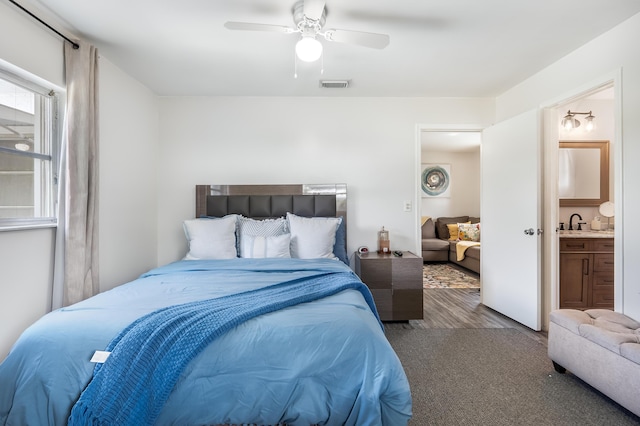 bedroom featuring a sink, visible vents, a ceiling fan, light wood finished floors, and ensuite bath