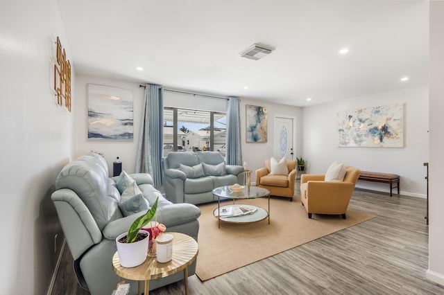 living area with recessed lighting, visible vents, baseboards, and wood finished floors