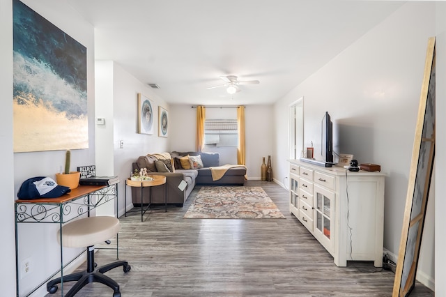 living area with dark wood-style flooring, visible vents, ceiling fan, and baseboards