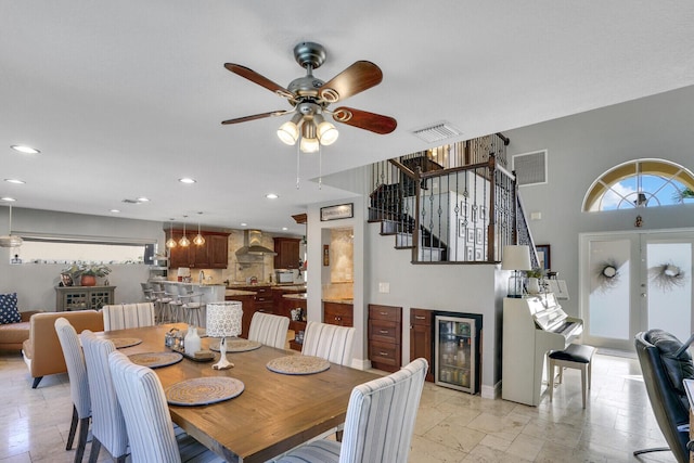 dining space with recessed lighting, beverage cooler, visible vents, and stairway