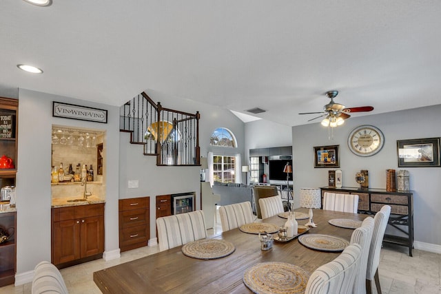 dining area with baseboards, visible vents, lofted ceiling, ceiling fan, and a bar