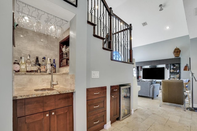 bar featuring tasteful backsplash, beverage cooler, indoor wet bar, and a sink