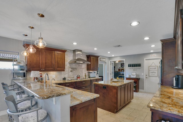 kitchen with black electric stovetop, visible vents, light stone countertops, a peninsula, and wall chimney exhaust hood