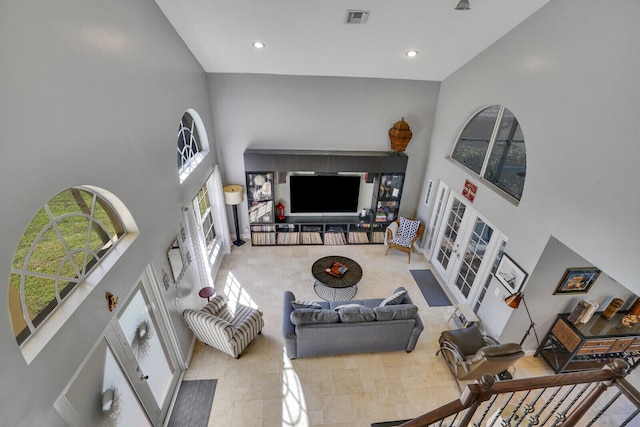 living room featuring a high ceiling, visible vents, and recessed lighting