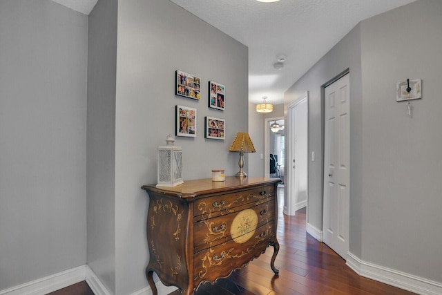 hallway featuring wood-type flooring and baseboards