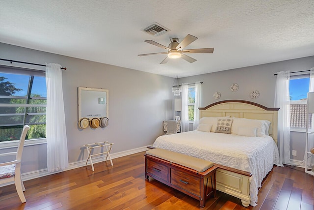 bedroom with multiple windows, visible vents, and dark wood-style flooring