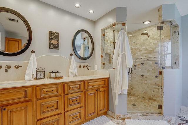 bathroom with double vanity, a shower stall, visible vents, and a sink